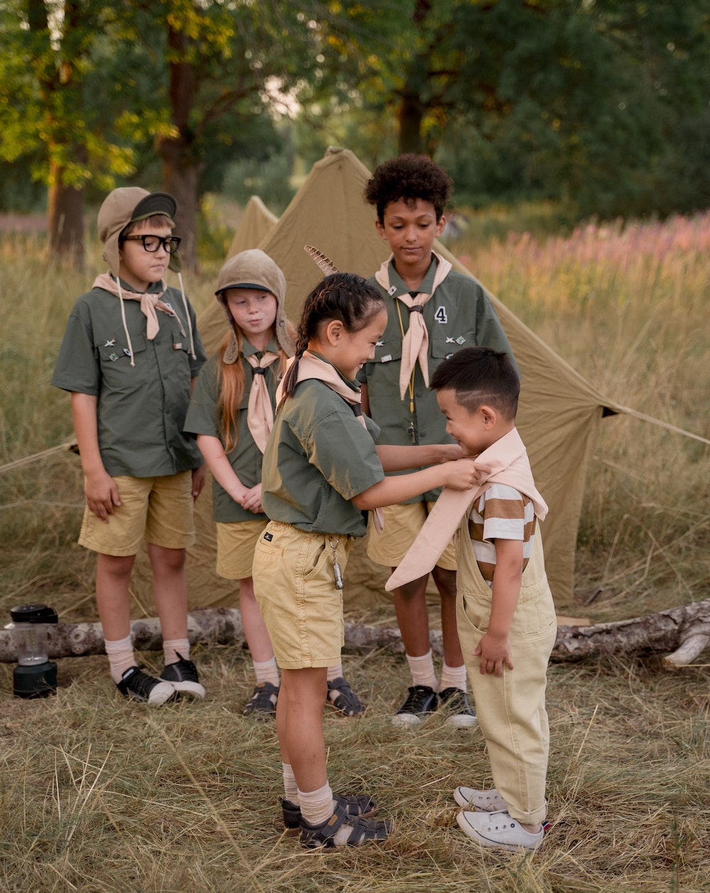 Children dressed in scout uniforms. A girl is helping a little boy tie his neckerchief